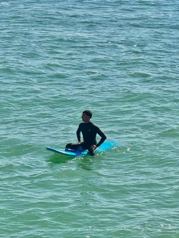Zoubair sitting on his surfboard in the water